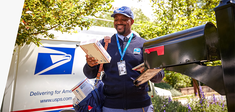 Letter carrier ready to deliver packages unloaded from the back of a USPS Next-Generation Delivery Vehicle.